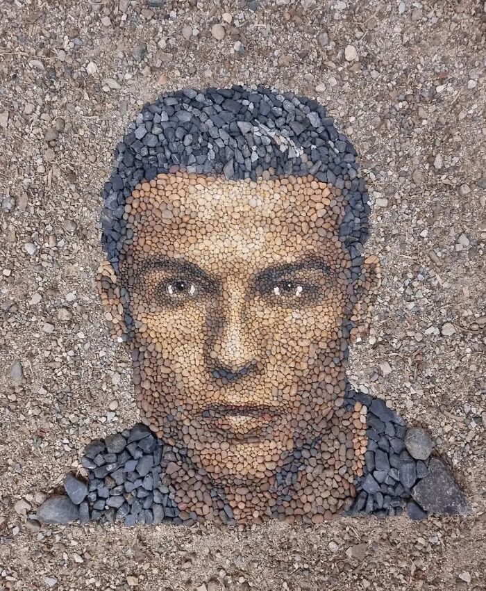 Intricate temporary mosaic of a face made from stones and pebbles by a British artist.