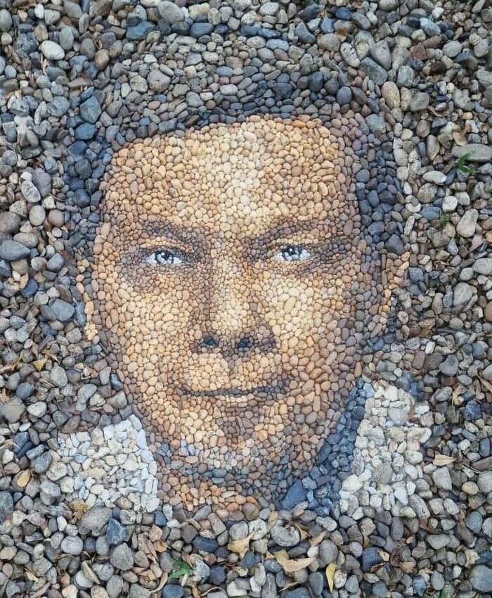 Intricate pebble mosaic by a British artist, depicting a face using various colored stones and pebbles.