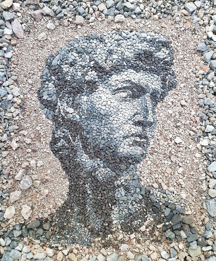 Pebbles arranged into a detailed mosaic depicting a classical sculpture's face by a British artist.