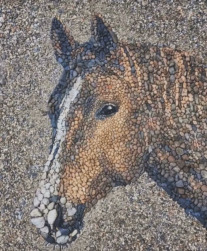 Pebble mosaic of a horse's head on gravel, created by a British artist using stones and pebbles.