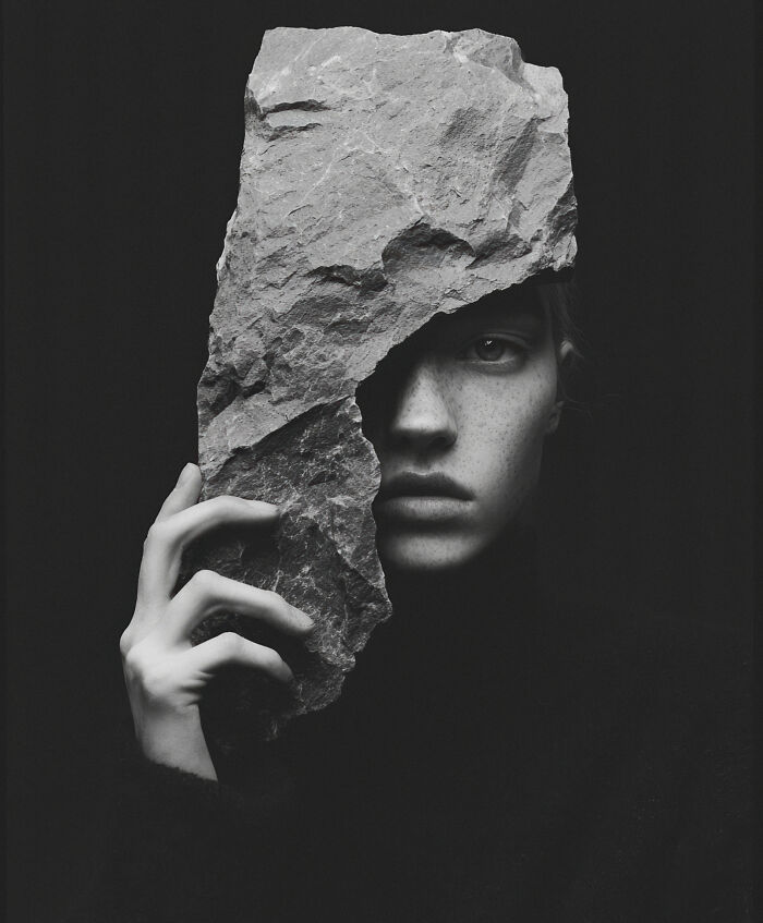 A mysterious AI image features a person's face partly obscured by a jagged rock, highlighting artistic creativity.