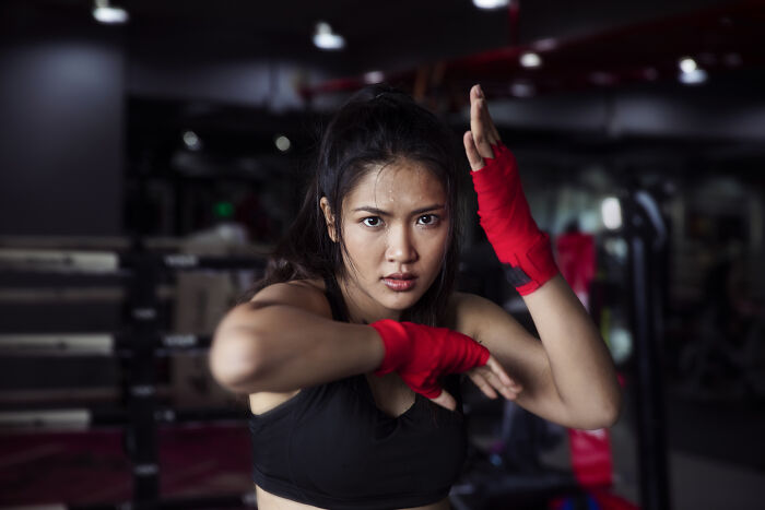 Woman in gym with red boxing wraps, defying societal norms, captured by photographer over 12 years.