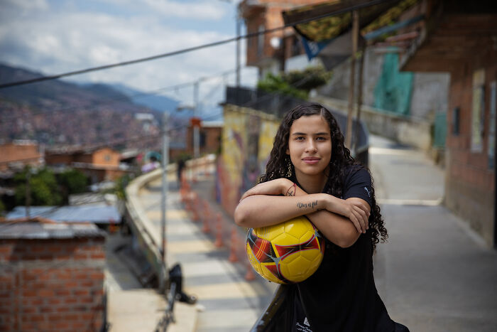 Young woman with a soccer ball in an urban setting, symbolizing defiance of society's rules.
