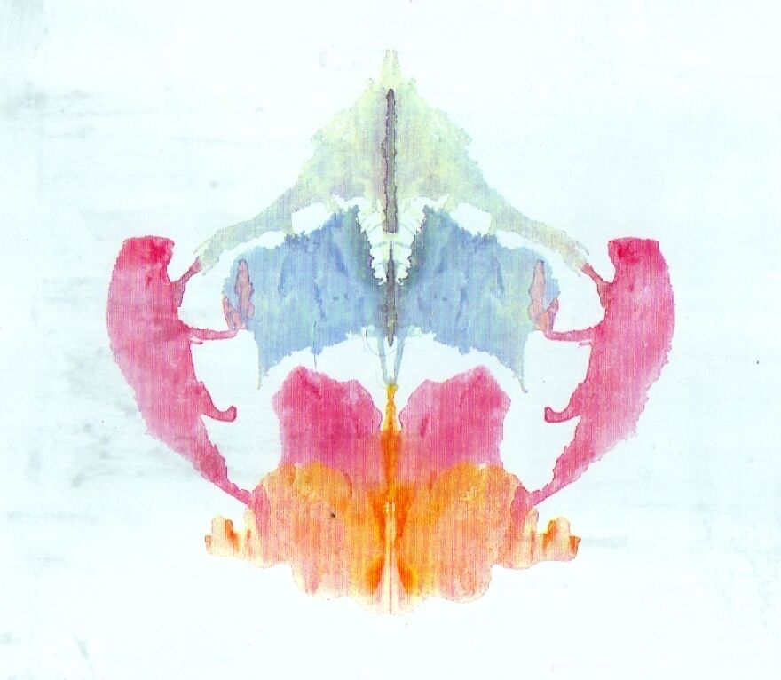 Colorful Rorschach inkblot featuring symmetrical shapes in blue, red, and orange hues.
