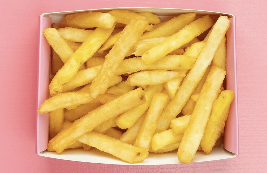 A box of crispy golden fries on a pink background, highlighting the best way to enjoy a snack.