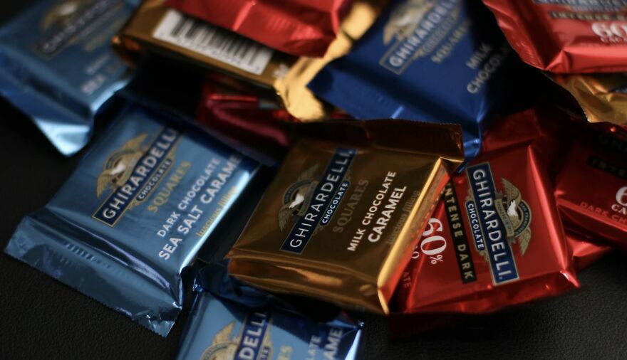 Assorted Ghirardelli chocolates on a dark surface, highlighting rich caramel and sea salt flavors.