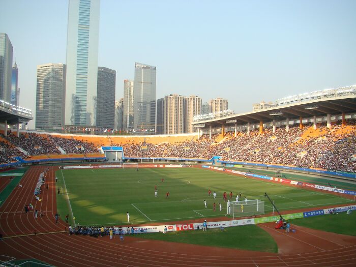 Soccer stadium filled with fans during a match, surrounded by city skyscrapers, showcasing iconic cathedrals of soccer.