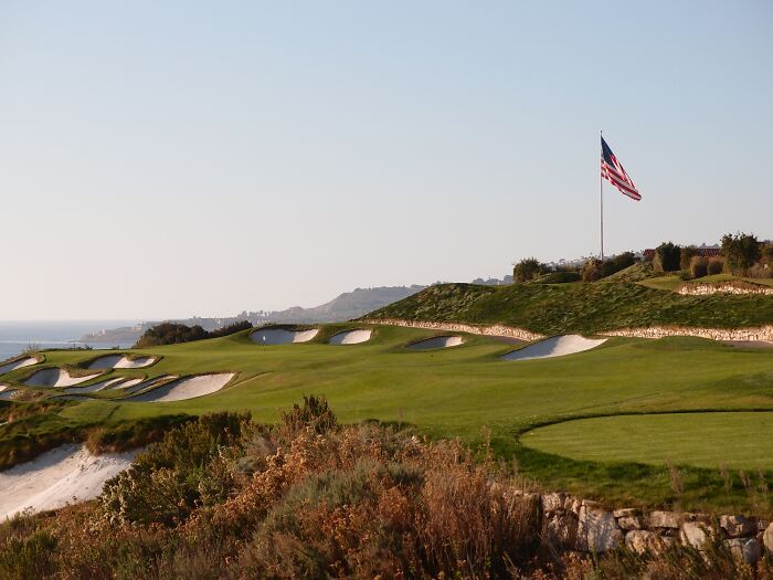Scenic golf course with rolling greens and an American flag, a sought-after destination for golfers worldwide.