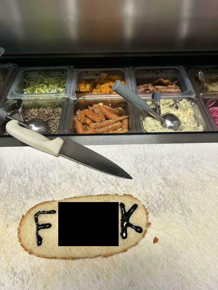 Bread slice with explicit icing text in a food service kitchen setting.
