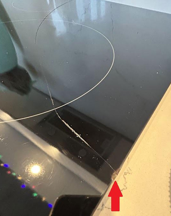 C*****d glass stovetop with visible damage, highlighted by a red arrow, illustrating an expensive accident.