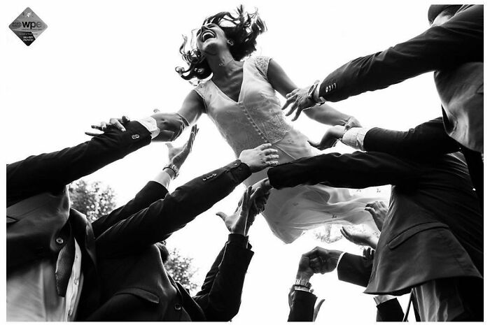 Bride in a joyful moment being lifted by groomsmen, capturing a precious wedding photograph by Jordi Tudela.