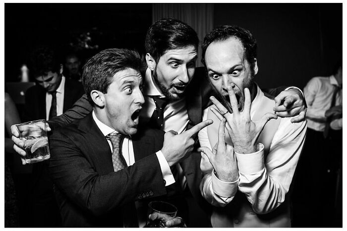 Men in suits express surprise, showcasing outstanding wedding photographs capturing moments of love.