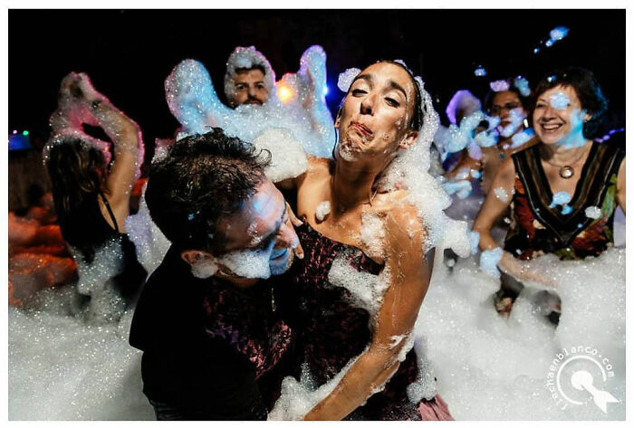 People celebrating with foam at a lively wedding party, capturing joyous moments of love and fun.