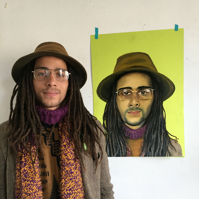British artist with hat poses beside his expressive portrait on a yellow background.