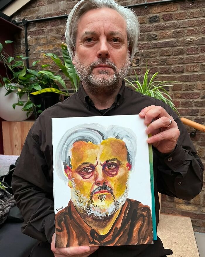 British artist holding an expressive portrait painting, showcasing his distinctive style.