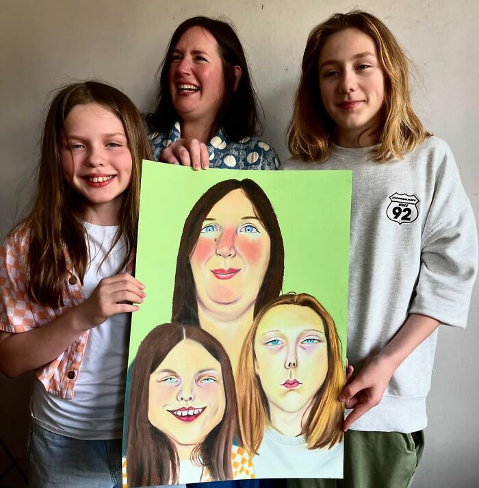 British artist's expressive portrait held by smiling family against a plain wall.