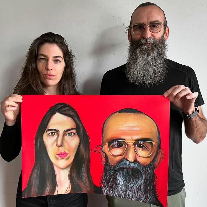 Two people holding an expressive portrait with bold colors, highlighting their features distinctly.