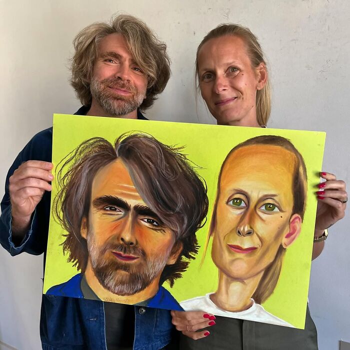 Two people holding expressive portraits by a British artist, showcasing vibrant and detailed features.