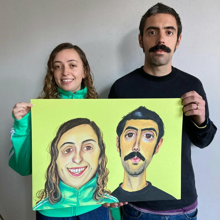 A British artist's expressive portrait held by two smiling people, showcasing unique facial features.