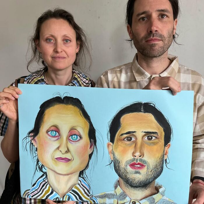 Two people holding a vibrant, expressive portrait drawing, showcasing the style of a British artist.