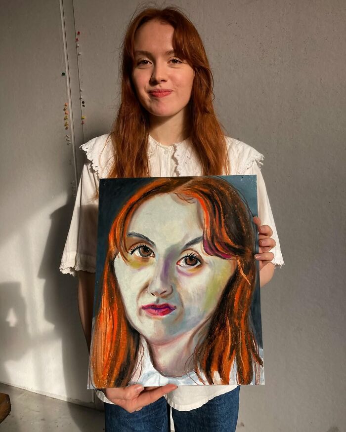 A British artist holding an expressive portrait.
