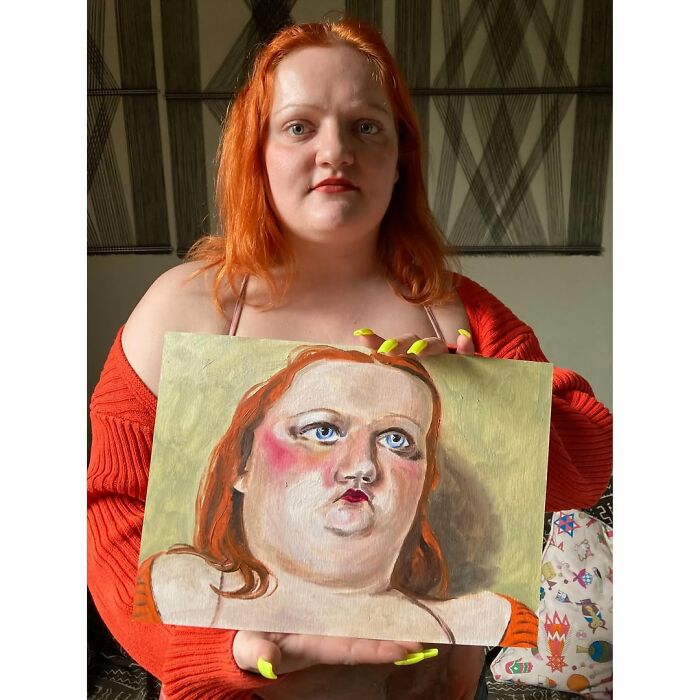 A British artist holding an expressive portrait with bold features and vivid colors.