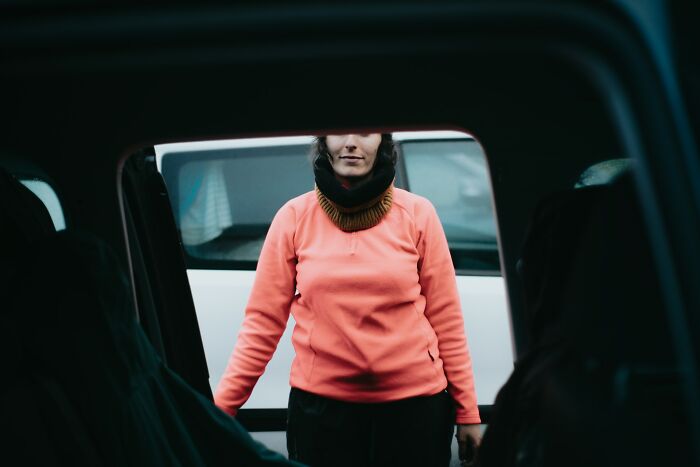 A person in a pink sweater viewed through a car window, emphasizing awareness of sudden dizziness.