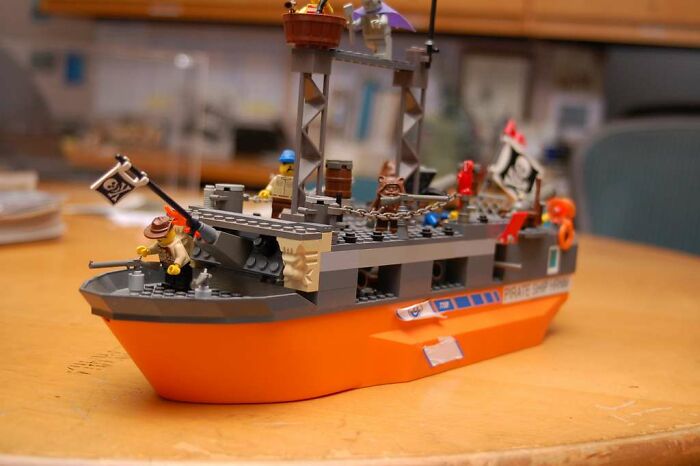 Lego pirate ship model on a wooden table, featuring playful details and miniature pirate figures.
