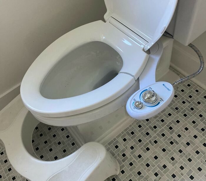 Bidet attachment on a toilet with a footstool, enhancing comfort, under $500 purchase.