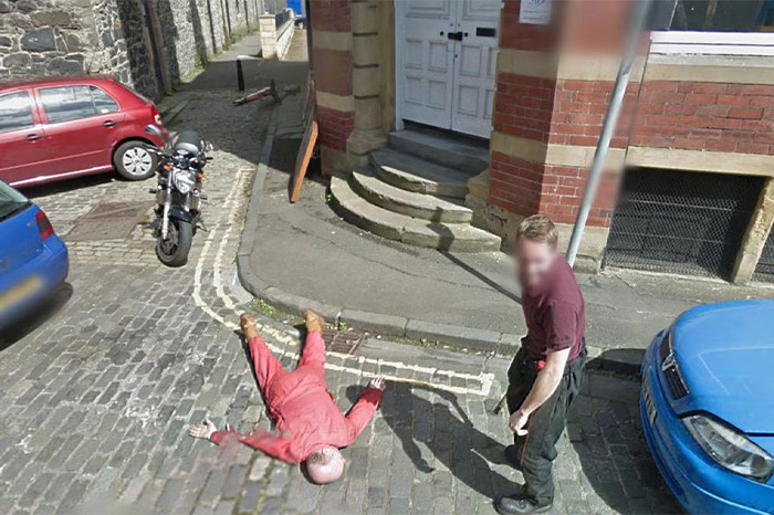 Two people on a cobblestone street, one lying down, captured by Google Earth in a strange scene.