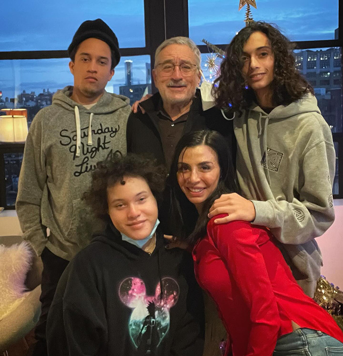 Group photo featuring Robert De Niro with family, including son, in a casual setting indoors. Group photo featuring Robert De Niro with family, including son, in a casual setting indoors.