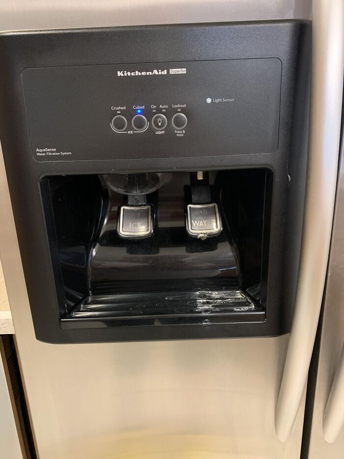 Fridge water and ice dispenser with buttons, typical in middle-class home kitchens.