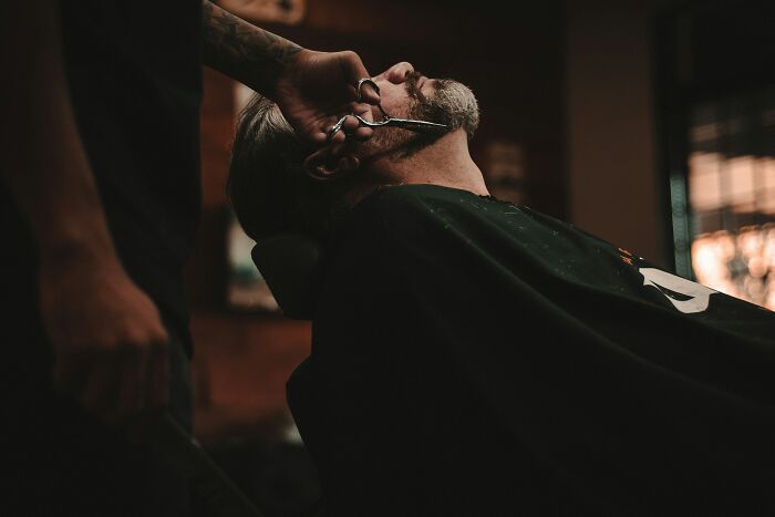 Man getting a shave at a barbershop, a frugal hack not worth the effort.