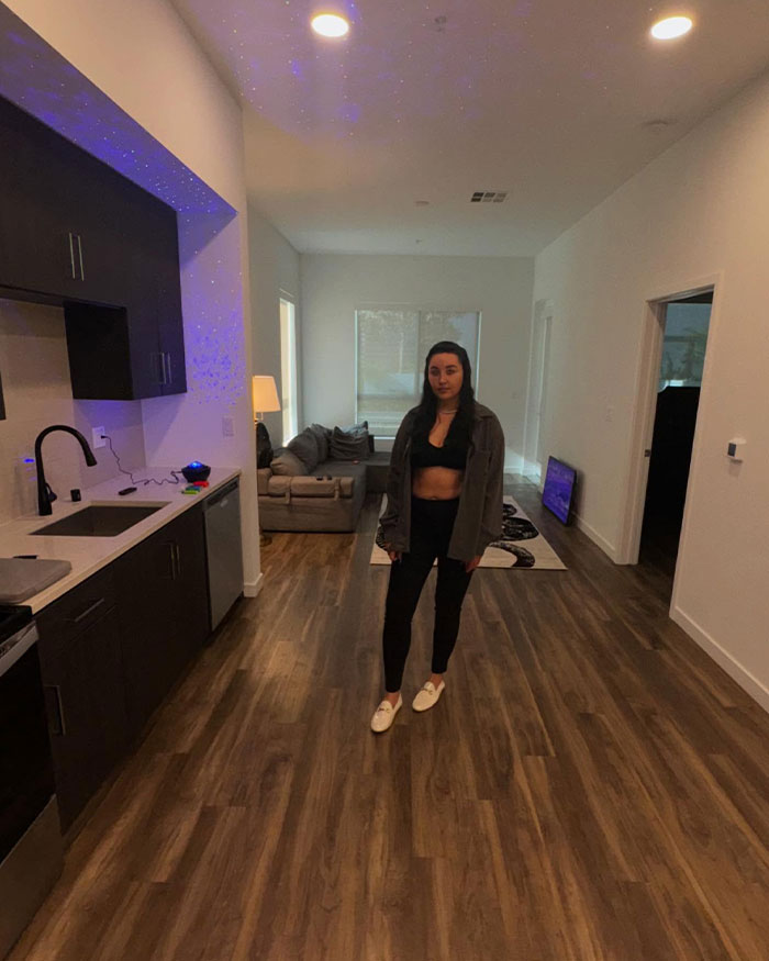 Amanda Bynes in casual attire stands in a modern kitchen, reflecting a lifestyle different from her Hollywood past.