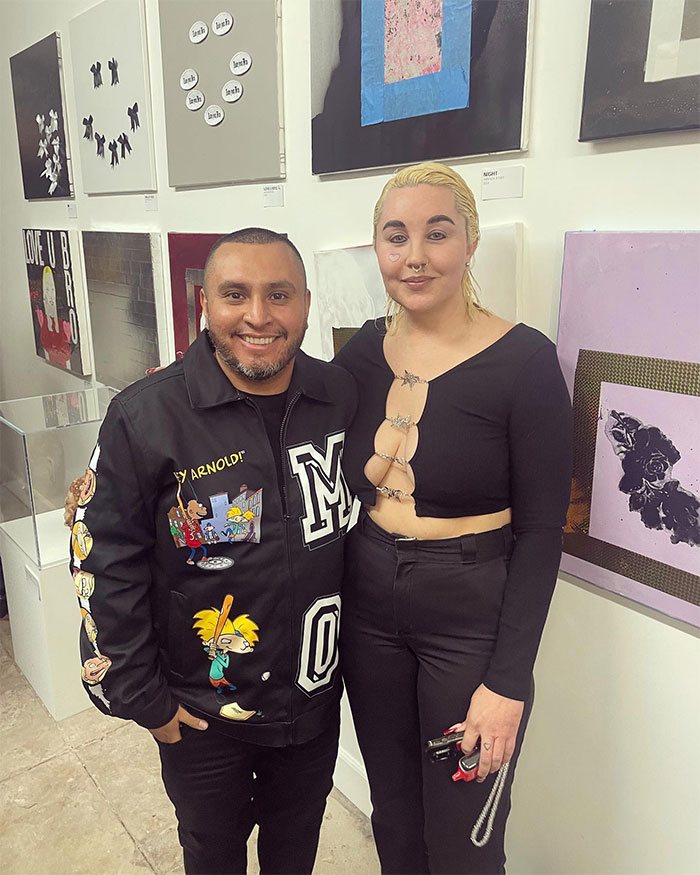 Two people including Amanda Bynes pose in a modern art gallery setting, showcasing a life distinct from Hollywood.