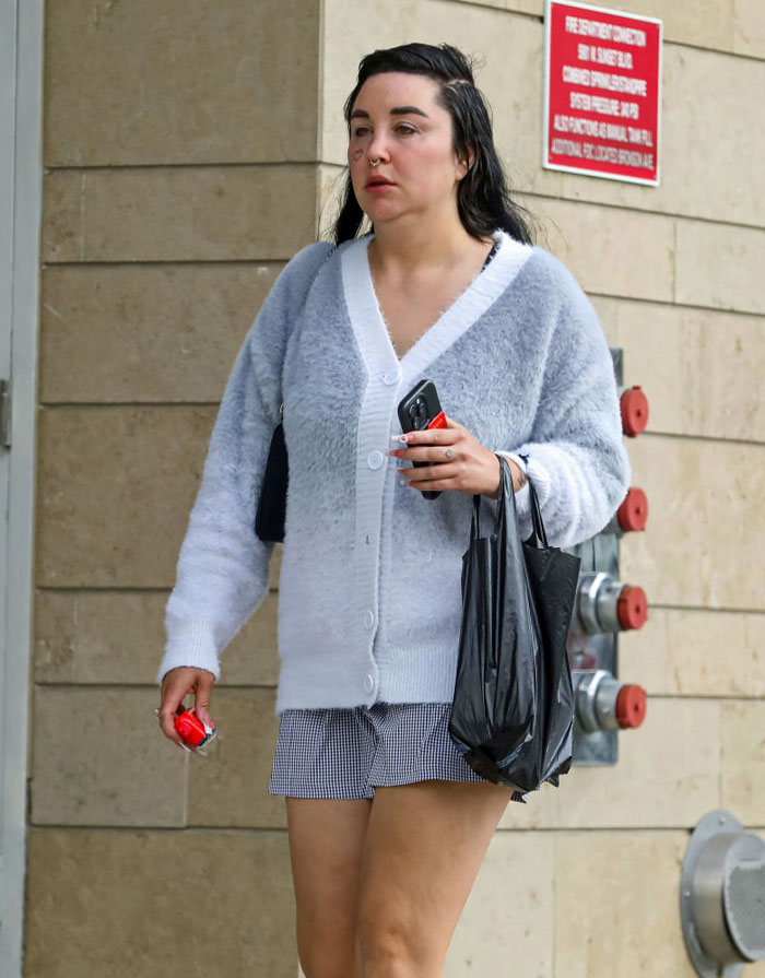 Amanda Bynes in casual attire holding a phone and bag, symbolizing a life beyond Hollywood's glamor.