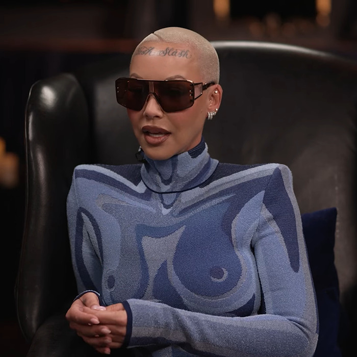 Amber Rose in an abstract-patterned outfit and sunglasses, seated, discussing Kanye West's views on provocative fashion.