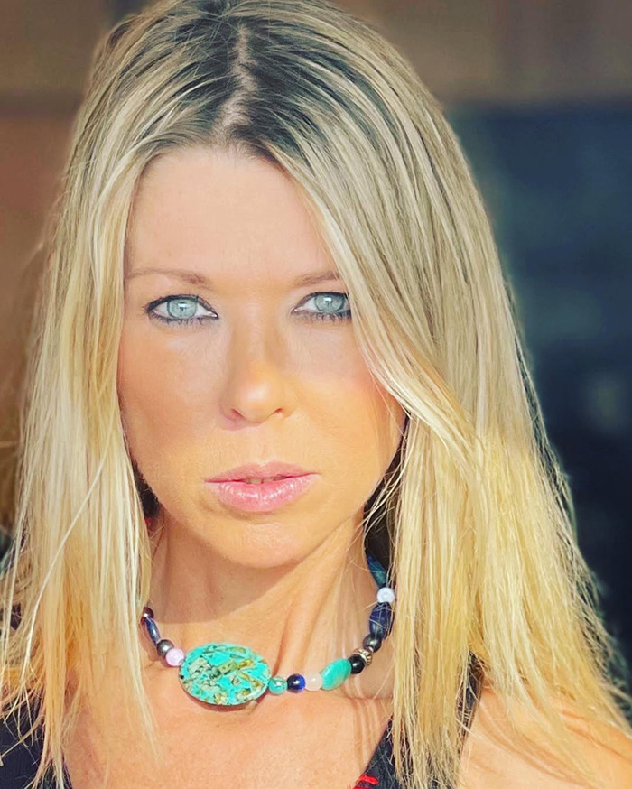 American Pie star at premiere, wearing a vibrant necklace, with blonde hair under natural lighting.