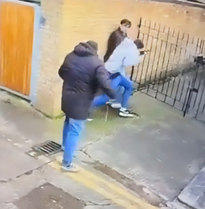 Irish horse carriage driver in altercation with tourists near a brick wall and metal fence.