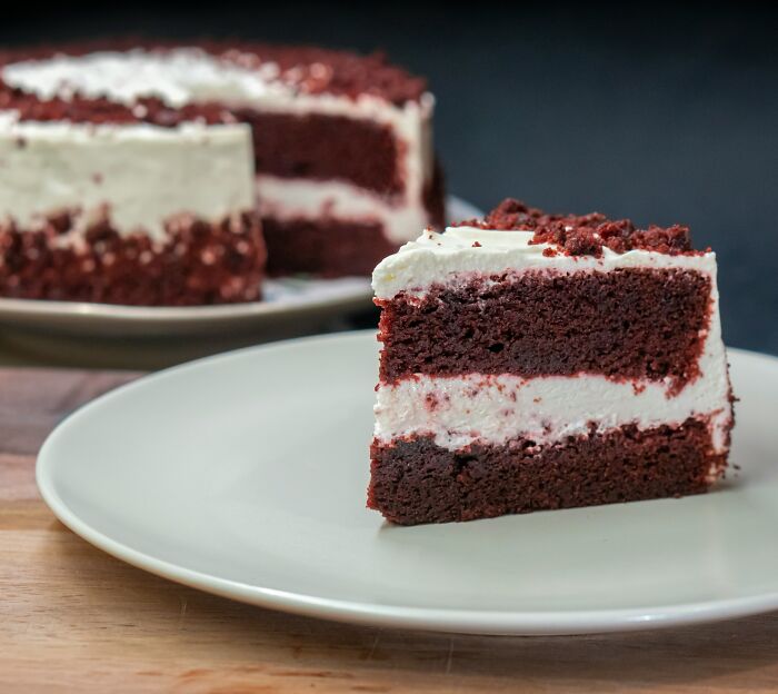 A slice of red velvet cake with cream cheese frosting on a plate, popular worldwide but not favored by everyone.