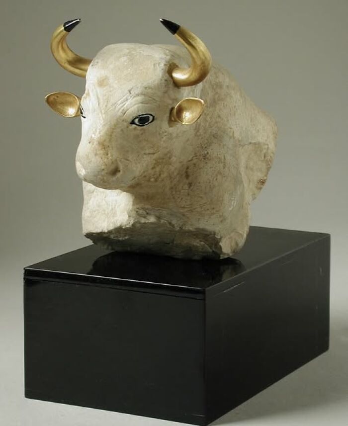 Ancient bull sculpture with gold horns on display, showcasing craftsmanship of early civilizations.
