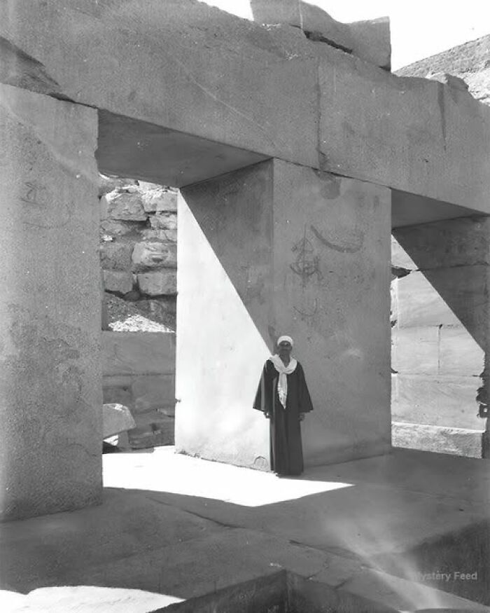 Person standing in ancient stone structure, showcasing historical architecture.