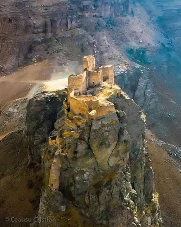 Ancient fortress ruins perched atop a steep cliff, showcasing remarkable historical architecture from ancient times.