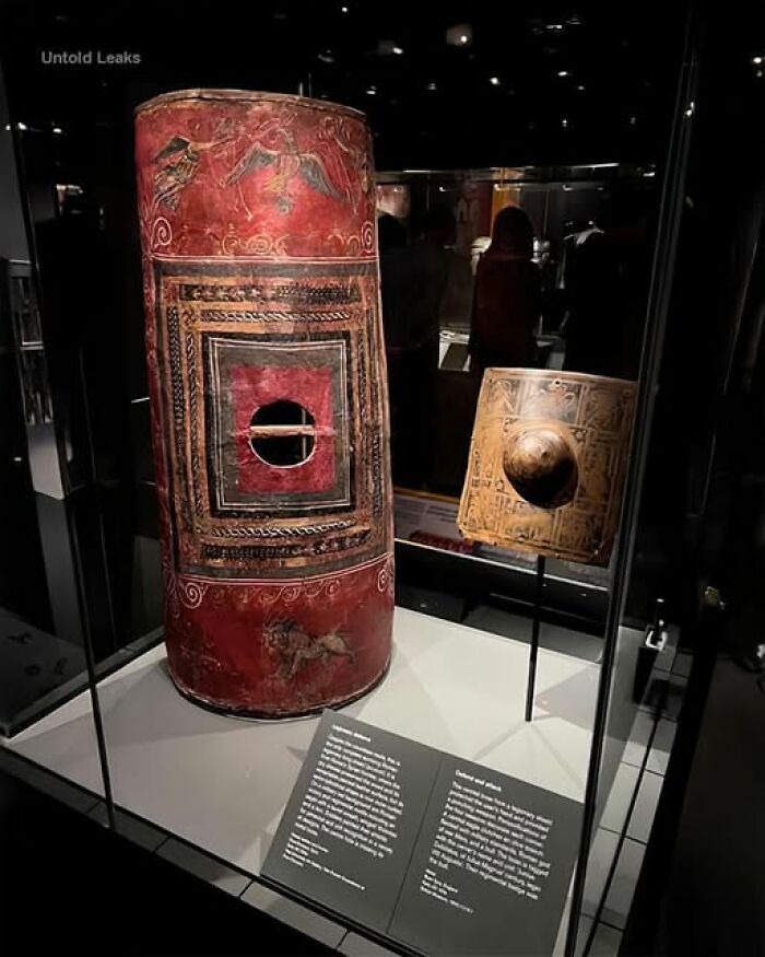 Ancient civilization shields on display, featuring intricate designs and patterns behind glass.