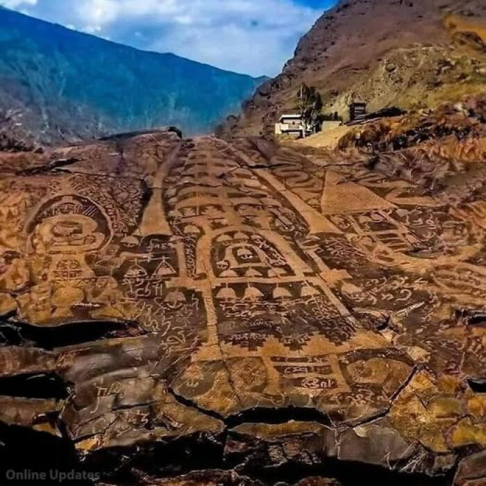 Ancient petroglyphs on rock surface with intricate designs, revealing secrets of past civilizations under a blue sky.