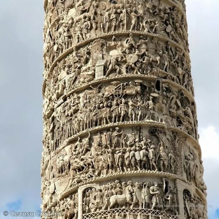 Ancient history relief carvings on a tall column, depicting historic scenes with intricate details.