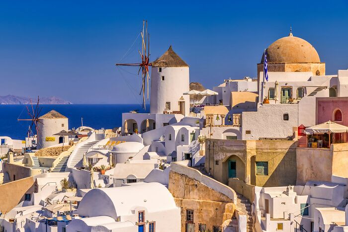 Scenic view of Santorini's iconic white buildings and windmills under a clear blue sky, noted by seasoned travelers.