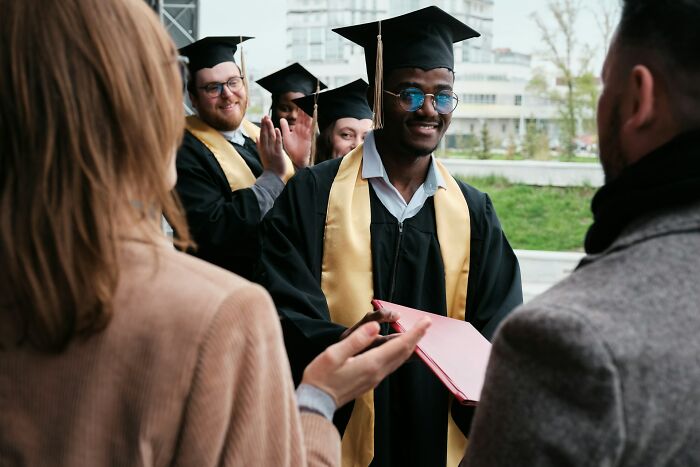 Graduates in caps and gowns celebrate, one receiving a handshake and diploma, embodying 'lifetime supply' achievement.