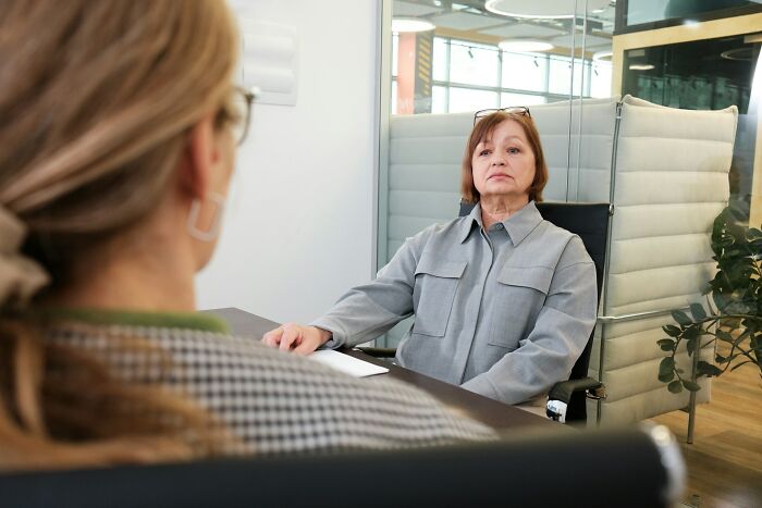 Two women during a tense job interview in a modern office, highlighting a challenging experience.