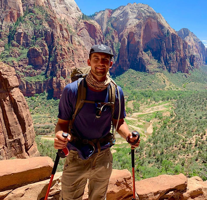 A man hiking with poles in a scenic mountain setting, wearing a hat and backpack. A man hiking with poles in a scenic mountain setting, wearing a hat and backpack.